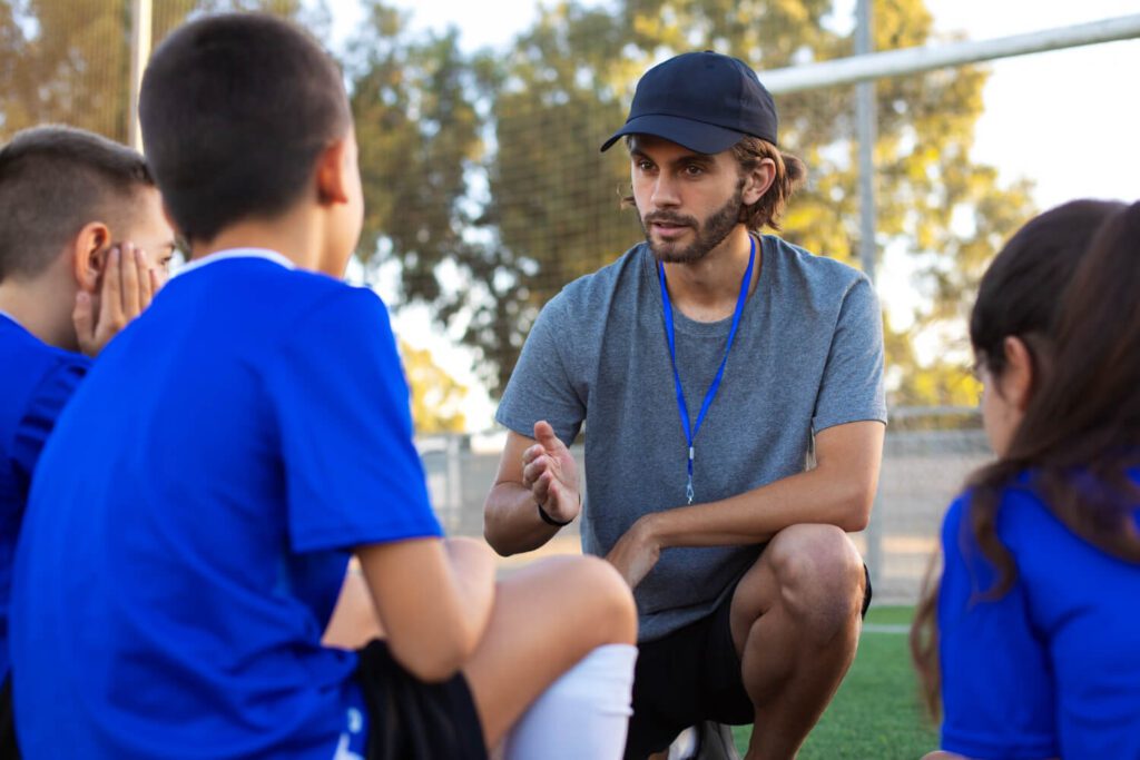 treinador de futebol de vista lateral ajudando criancas